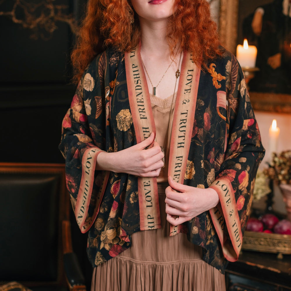 Woman in Heart of Gold Pixie Duster from Market of Stars, dark floral kimono with 'Friendship Love & Truth' trim.