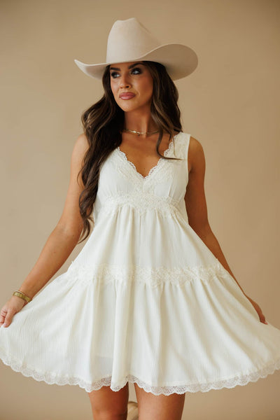 L9549 Slip Dress in Cream by By Together. Woman wearing a cream lace-trimmed slip dress and a light cowboy hat.