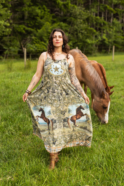 Woman wearing the Born To Run Bohéme Slip Dress by Market of Stars, featuring horse prints, in a field with a horse.