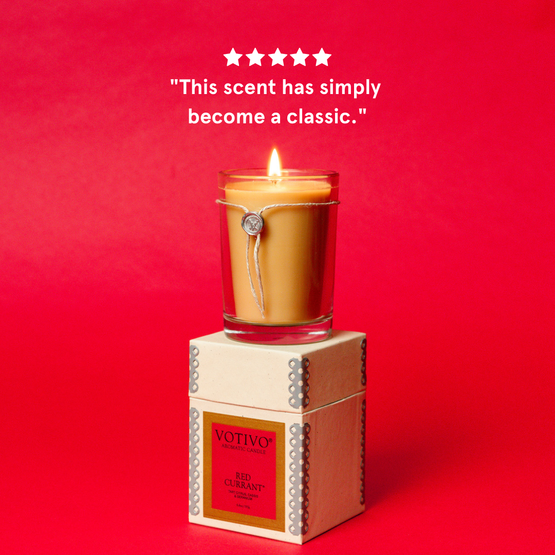 Votivo Red Currant Aromatic Candle, lit in a glass jar, atop its decorative box, with a 5-star customer review.