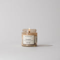 Lit Votivo Champaca Discovery Candle in a glass jar, featuring champa petals, patchouli & clove scent.