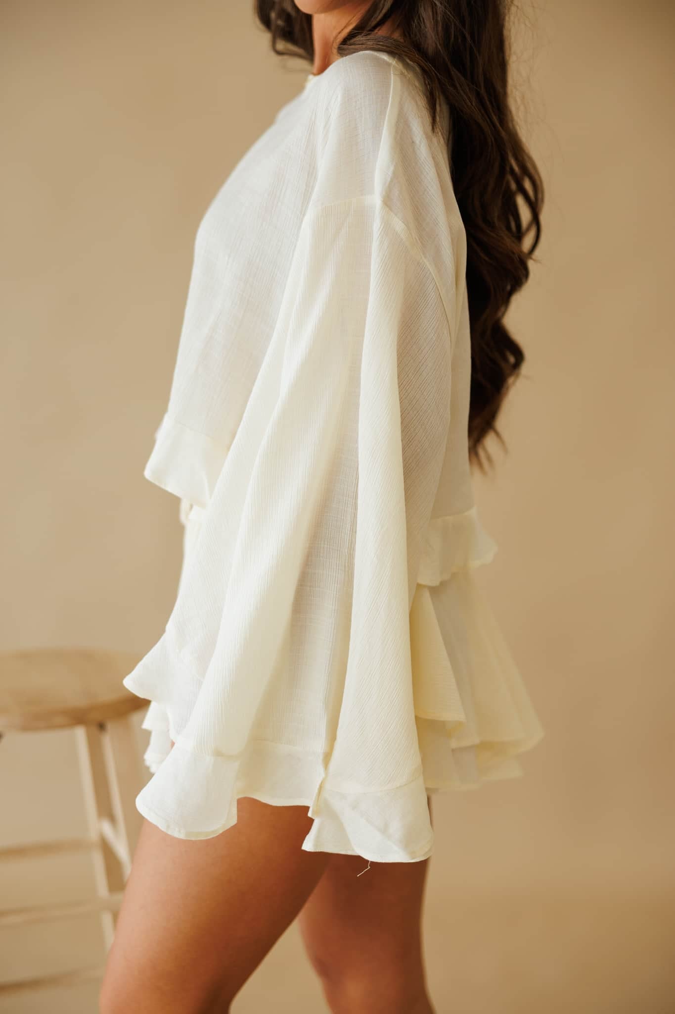 L9403T Cropped Blouse in Cream | By Together. Woman wearing a cream textured ruffled cropped blouse and matching shorts.