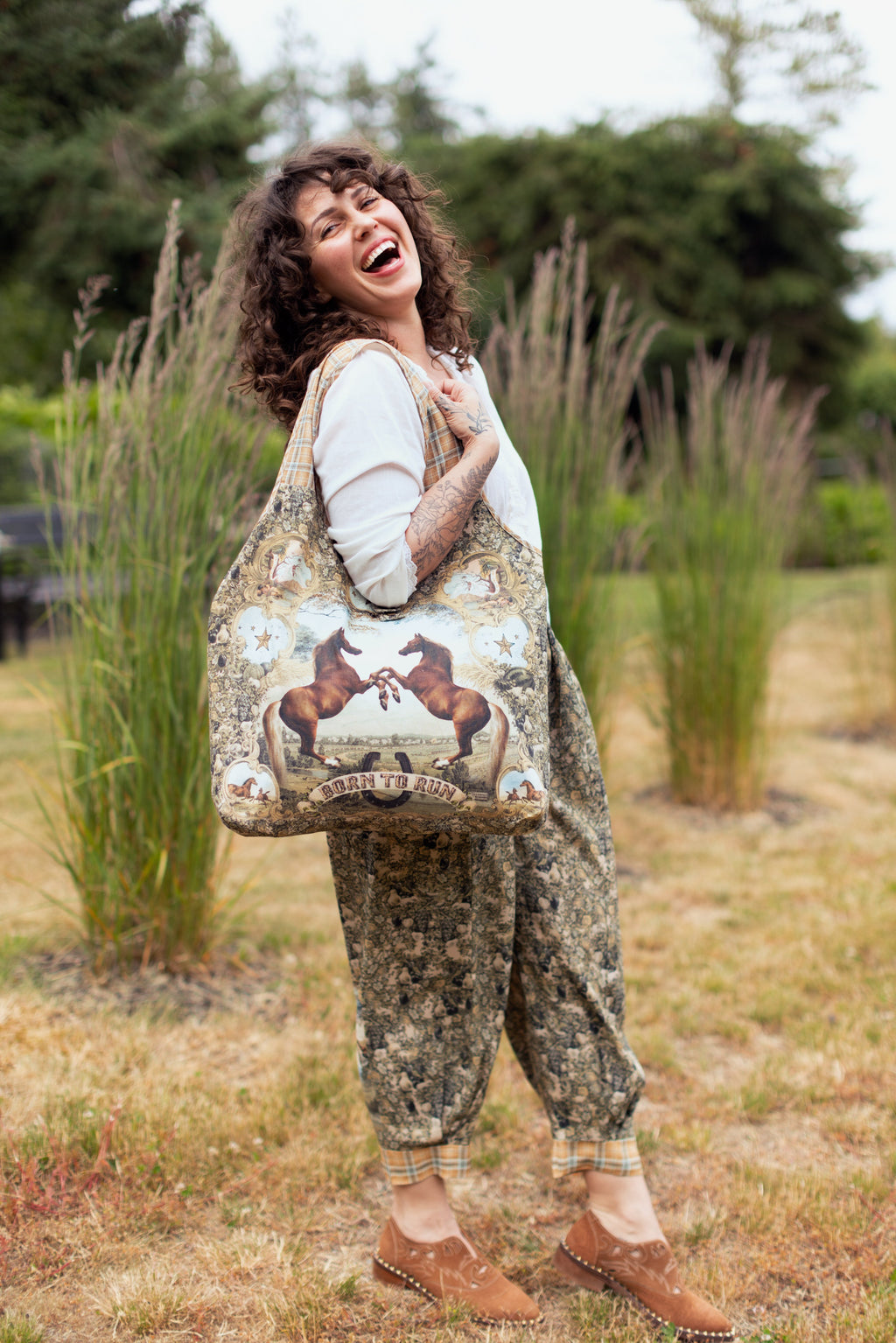 Born To Run Market Tote by Market of Stars: a happy woman carries a large tote with two horses and 'Born To Run' graphic.
