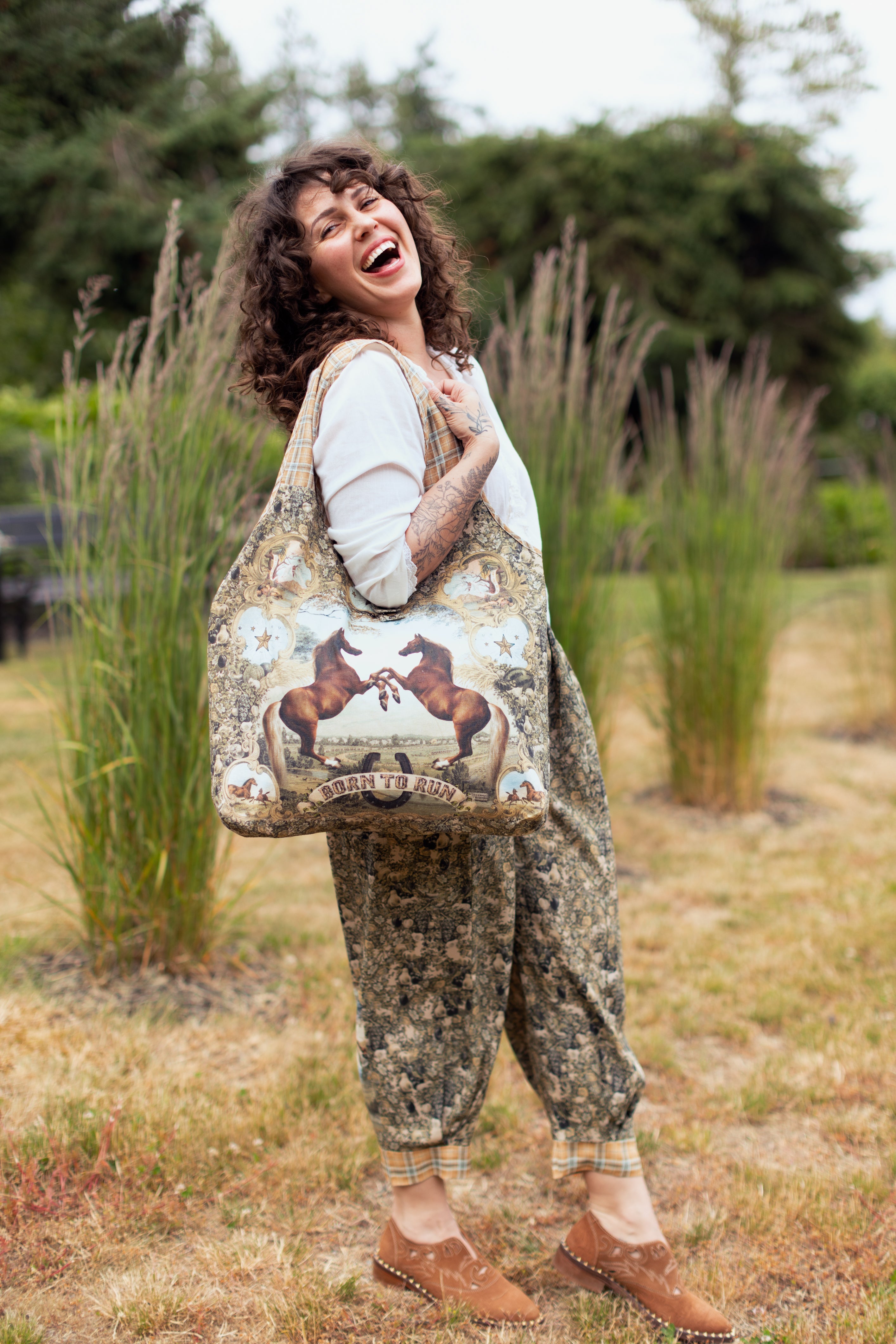 Born To Run Market Tote by Market of Stars: a happy woman carries a large tote with two horses and 'Born To Run' graphic.