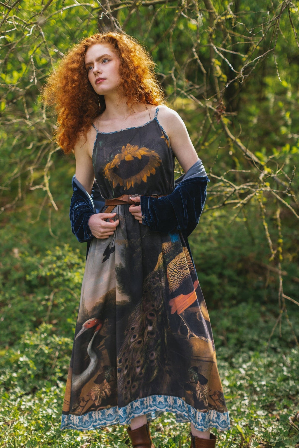 Wild Beauty Bohéme Slip Dress by Market of Stars with sunflower, peacock & crane print, worn by a redhead model in a lush setting.