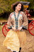 Woman wears Love Revolution Pixie Duster from Market of Stars, featuring colorful floral patterns, with a golden skirt and red cart background.