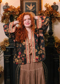 Woman in Heart of Gold Pixie Duster from Market of Stars, a dark floral kimono with 'LOVE & TRUTH FRIENDSHIP' trim, smiling.