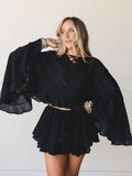 L9403T Cropped Blouse in Black by By Together, modeled with matching ruffled mini skirt and jewelry.