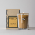 Lit Votivo Champaca Aromatic Candle in glass jar with twine & seal, next to its kraft box. Scent: Champaca Petals, Patchouli & Clove.