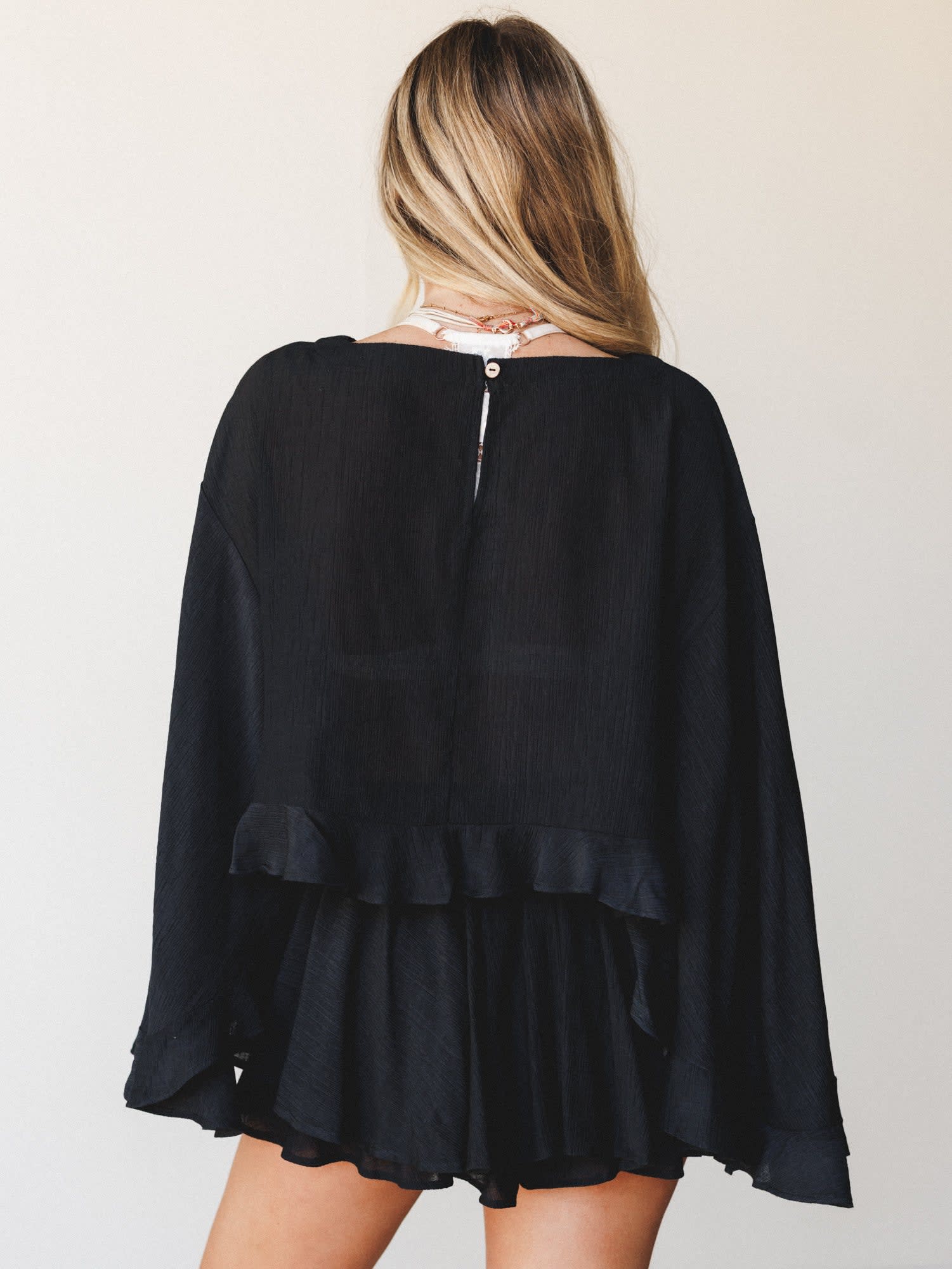 L9403T By Together Black Cropped Blouse with long loose sleeves and ruffled hem, shown from the back on a woman.