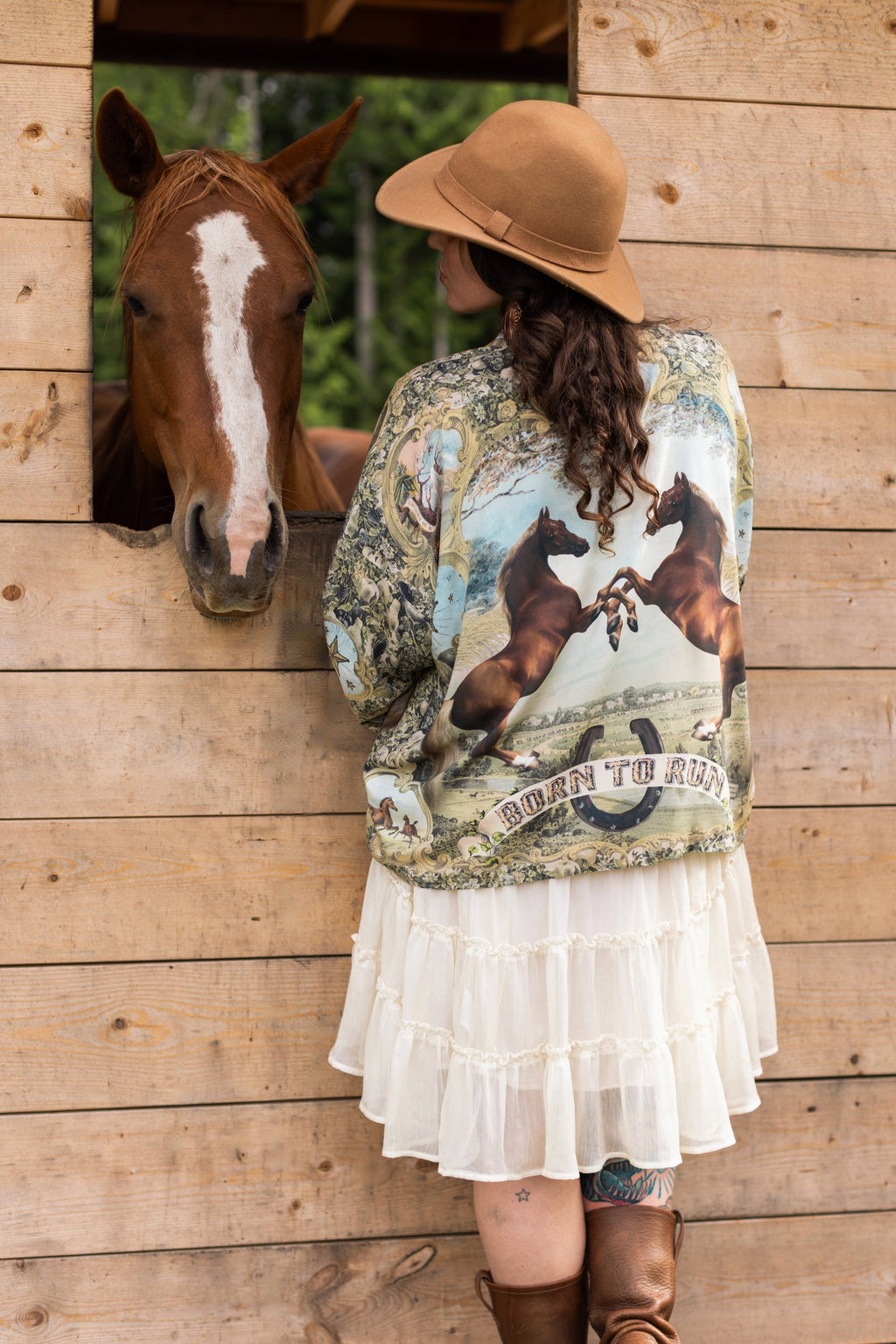 Born To Run Pixie Duster | Market of Stars on a woman with a hat, standing next to a horse peeking from a wooden stable.