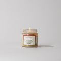 Votivo Red Currant Discovery Candle, 2.8 oz, tart citrus, cassis & geranium, burning wick, in a clear glass jar on white background.