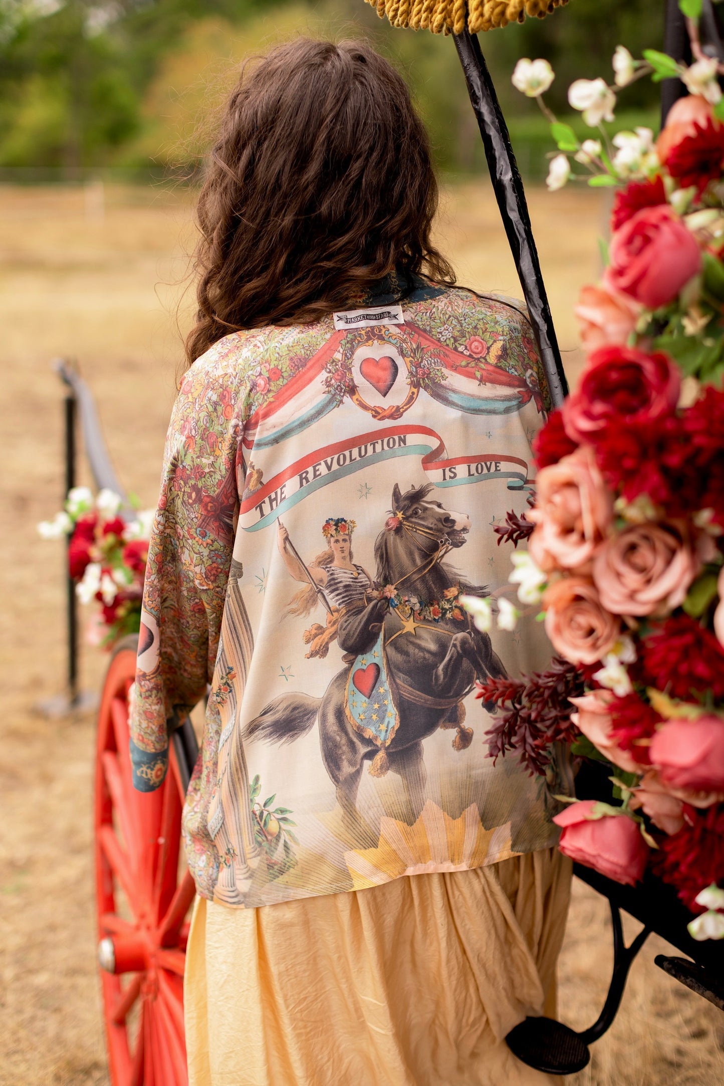 Market of Stars Love Revolution Pixie Duster on a woman, showing 'The Revolution Is Love' print with a woman on horseback.