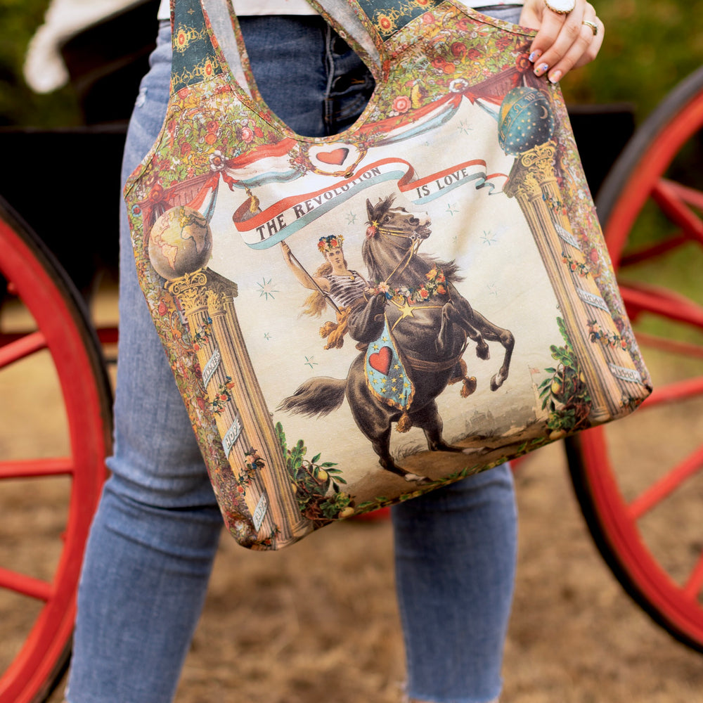 Love Revolution Market Tote with vintage art of a woman riding a horse under a banner saying 'THE REVOLUTION IS LOVE'.