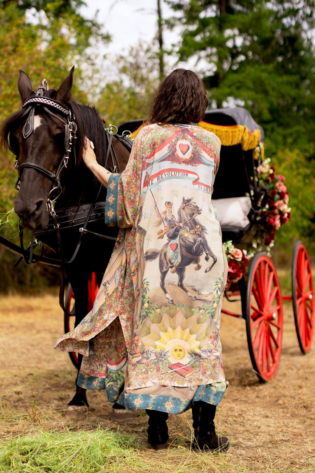 Boho-chic Love Revolution Opera Duster by Market of Stars with a unique revolution print, worn by a woman next to a horse & carriage.