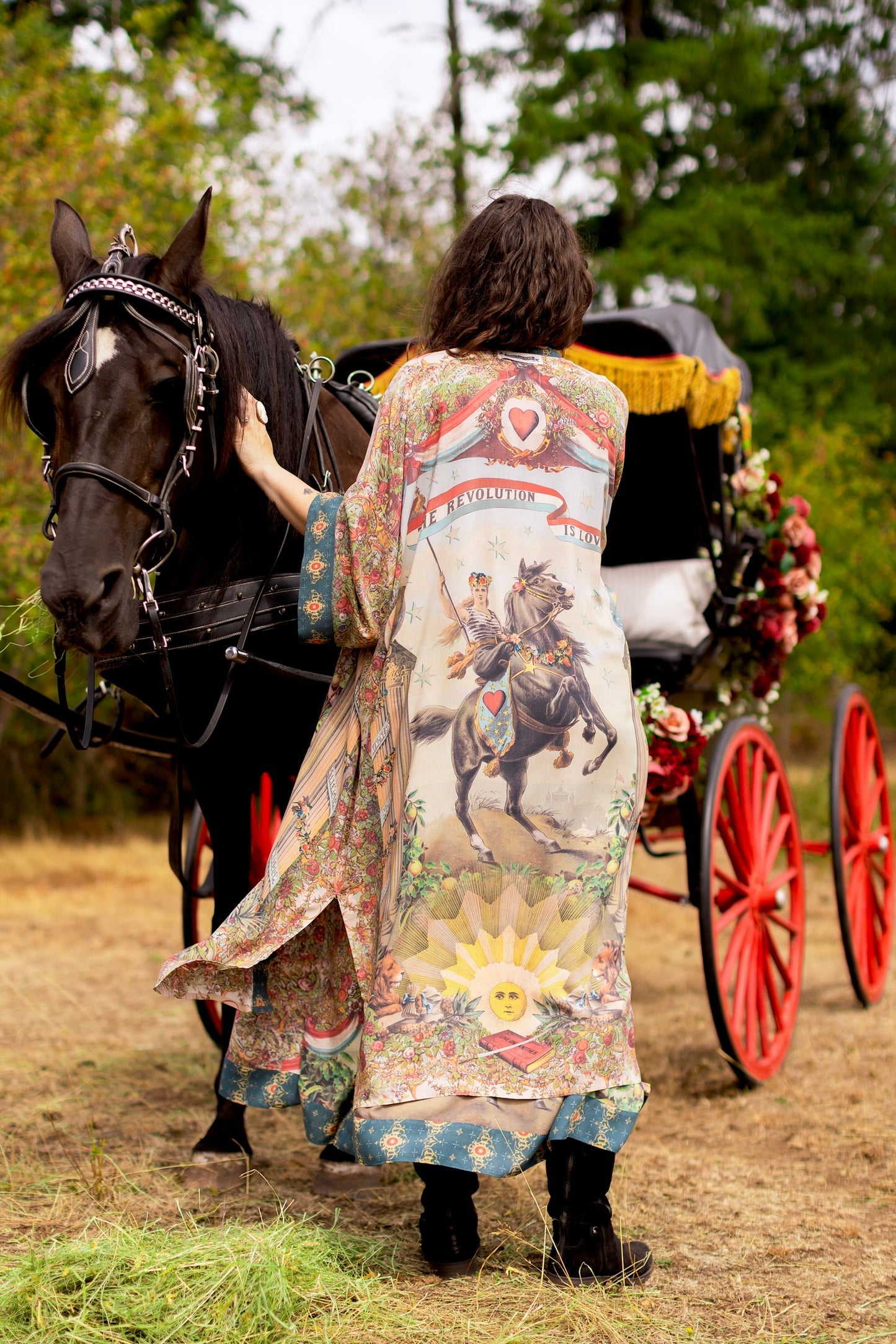 Boho-chic Love Revolution Opera Duster by Market of Stars with a unique revolution print, worn by a woman next to a horse & carriage.