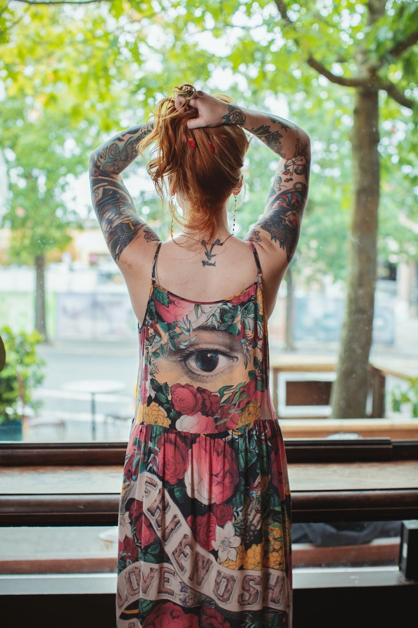 Friendship Love & Truth Bohéme Slip Dress by Market of Stars on a woman with red hair & full arm tattoos looking out window.