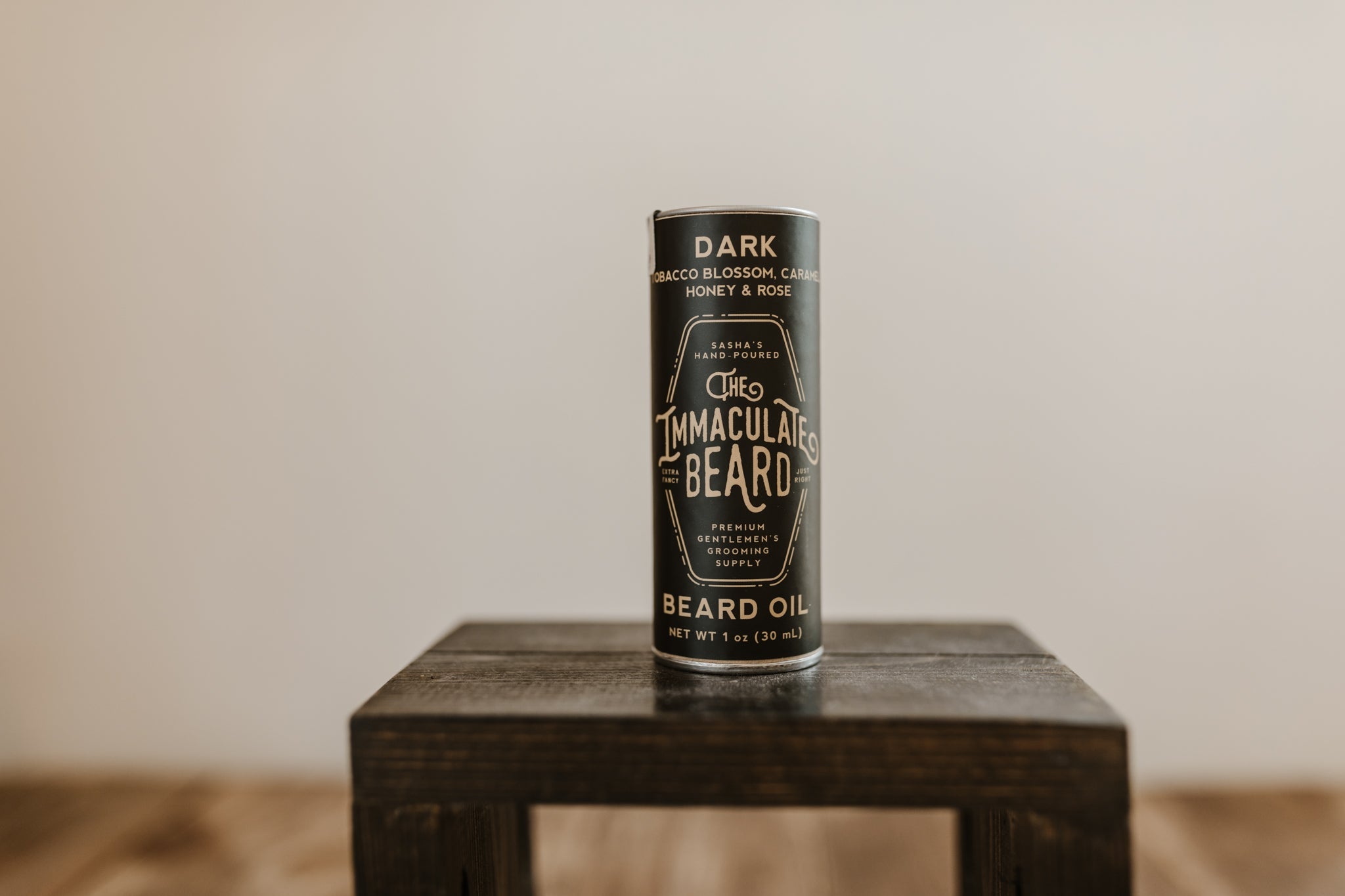 The Immaculate Beard Midnight Beard Oil with tobacco blossom, caramel, honey & rose scent on a wooden surface.