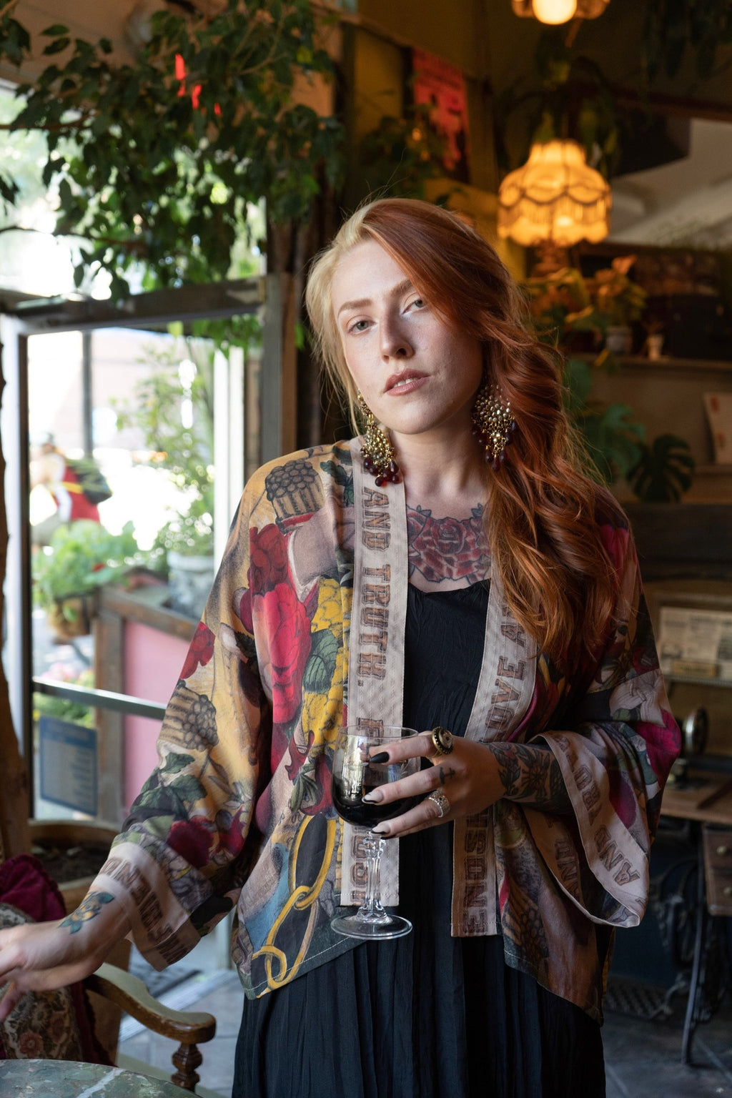Woman in Market of Stars' colorful "Friendship Love & Truth Pixie Duster" holding wine in a cozy setting.