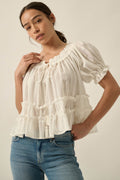 Woman models Promesa Precious Days Ruffle Babydoll Top in Off White, featuring gathered neckline, puff sleeves, and tiered ruffles.