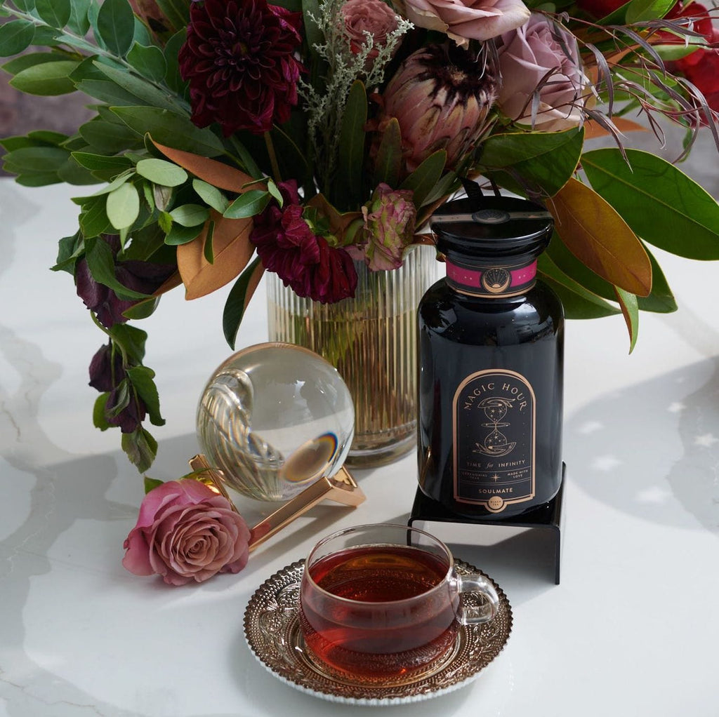 Magic Hour Soulmate Chocolate-Raspberry-Rose Black Tea bottle & cup, pink rose, crystal ball, & floral arrangement.