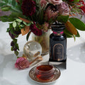 Magic Hour Soulmate Chocolate-Raspberry-Rose Black Tea bottle & cup, pink rose, crystal ball, & floral arrangement.