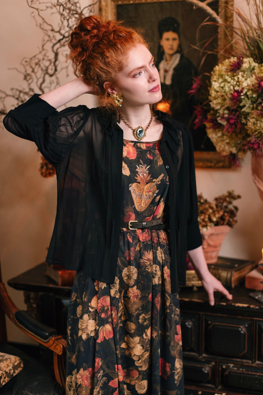 Red-haired woman in Market of Stars Heart of Gold Bohéme Slip Dress with sacred heart & floral print, and sheer black top.