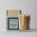 Votivo Smoked Wood & Amber Aromatic Candle in a glass holder with a burning flame, next to its brown box packaging.