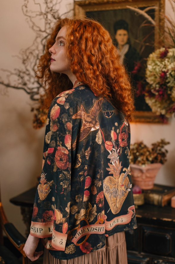 Market of Stars Heart of Gold Pixie Duster on a model, featuring dark fabric with detailed floral, sacred heart, and bird motifs.