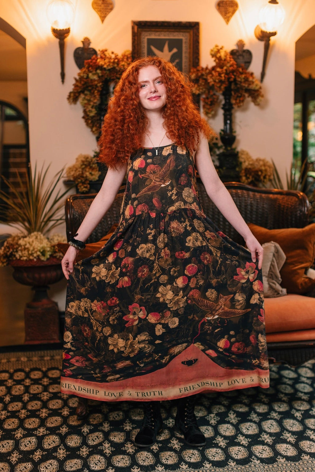 Woman in Heart of Gold Bohéme Slip Dress by Market of Stars, dark floral print with birds, 'FRIENDSHIP LOVE & TRUTH' on hem.