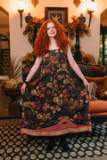 Woman in Heart of Gold Bohéme Slip Dress by Market of Stars, dark floral print with birds, 'FRIENDSHIP LOVE & TRUTH' on hem.