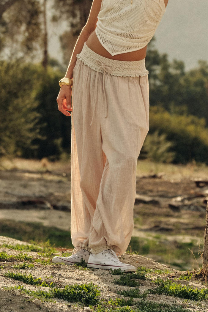 Natural Promesa Break Free Balloon Pants with a smocked waist and elasticated cuffs, styled with a white top and sneakers outdoors.