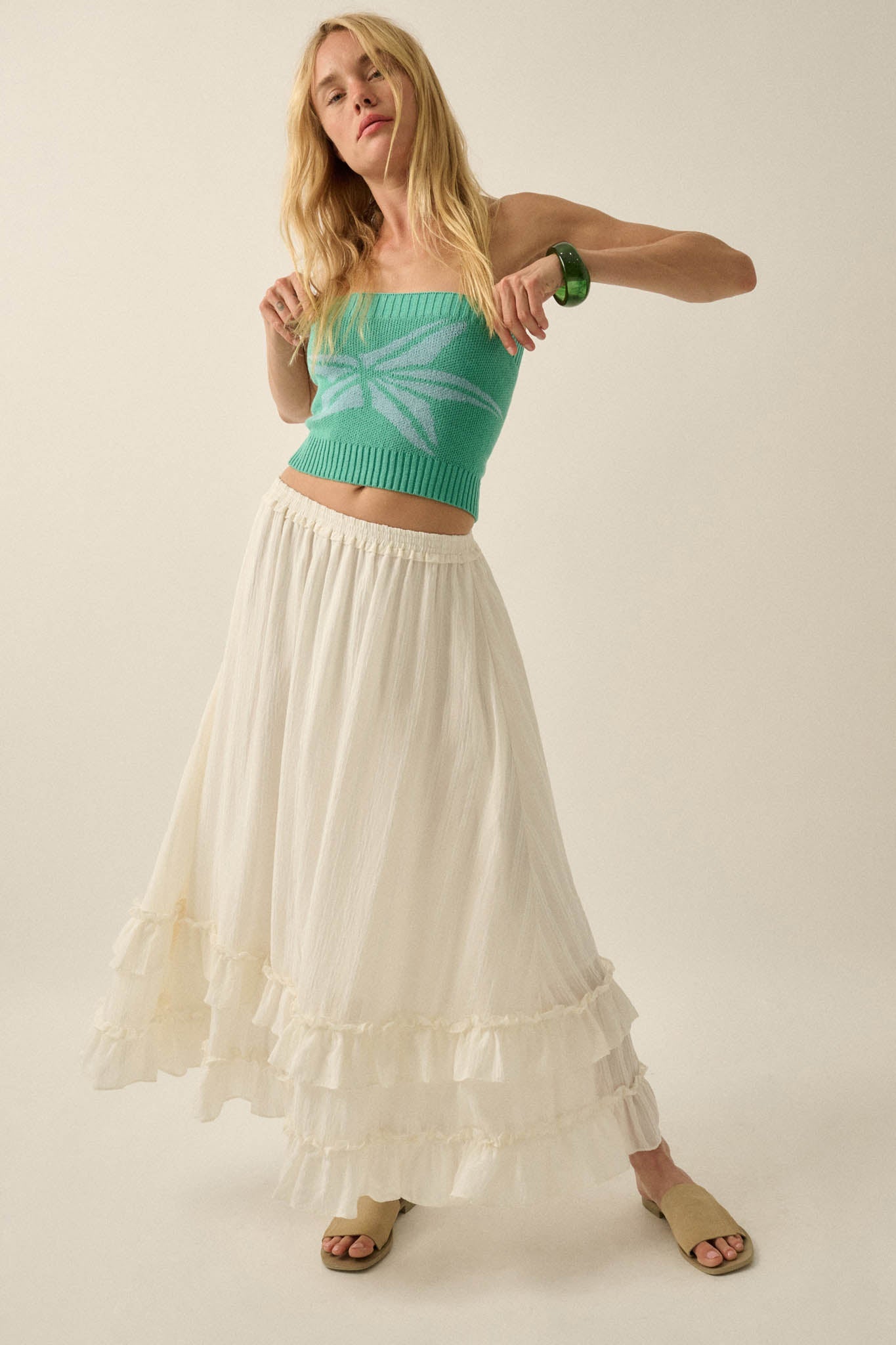 Pretty Precious Ruffle Maxi Skirt — Off White | Promesa. Model wears with a green crop top and tan sandals.