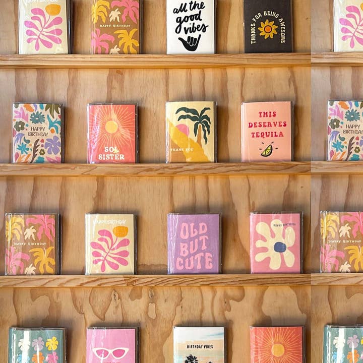 Happy Birthday Boho Sun Card | Daydream Prints on display with a variety of colorful, artistic greeting cards on wooden shelves.
