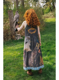 Wild Beauty Bohéme Slip Dress by Market of Stars, with peacock print, worn by a person holding a falcon outdoors.