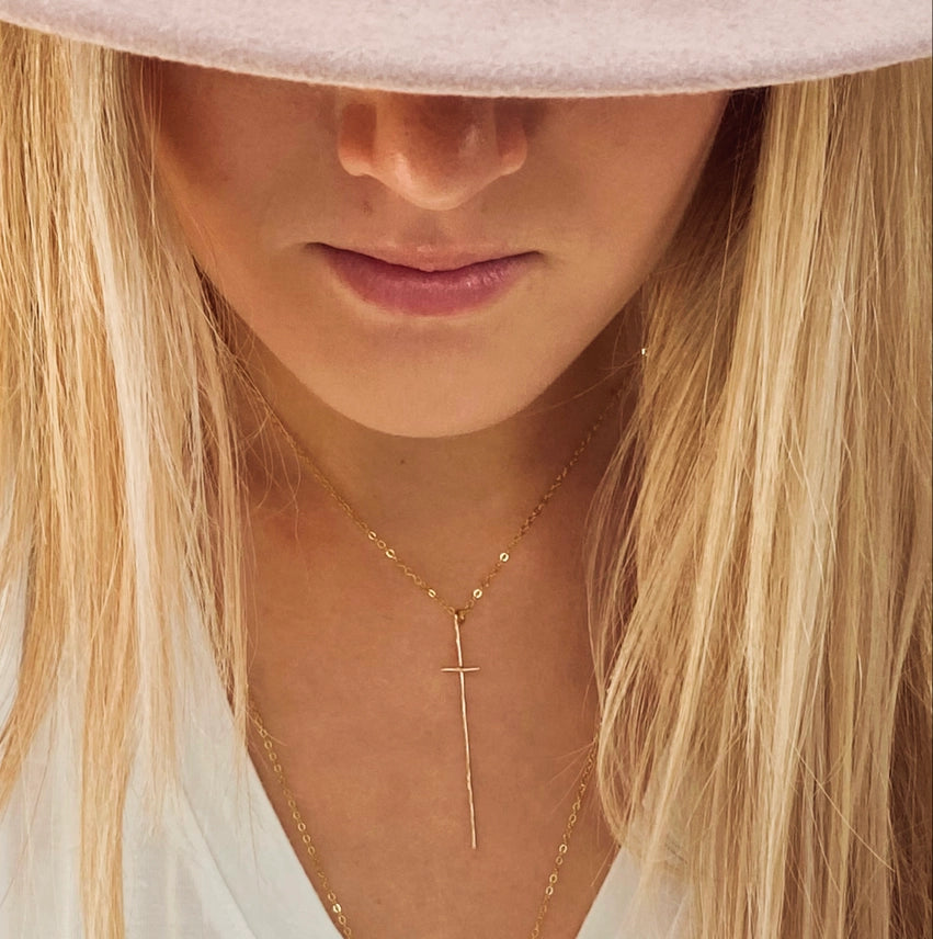 Modern Cross Necklace 14kt Gold Fill by bonnieboardman, a long vertical gold cross pendant on a woman with blonde hair.