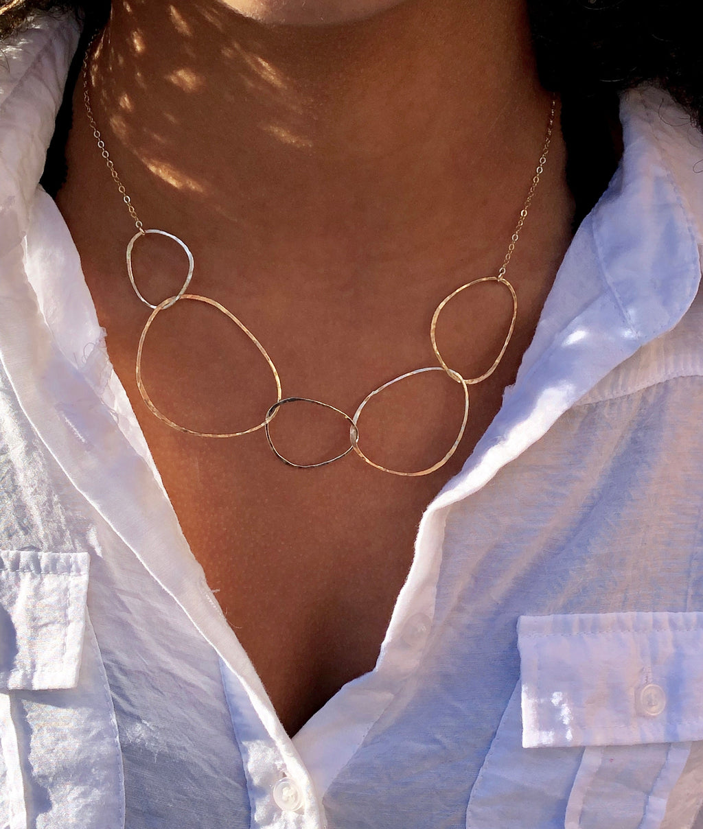 River Rock Necklace 14kt Gold Fill by bonnieboardman, featuring multiple hammered organic rings, worn by a model.